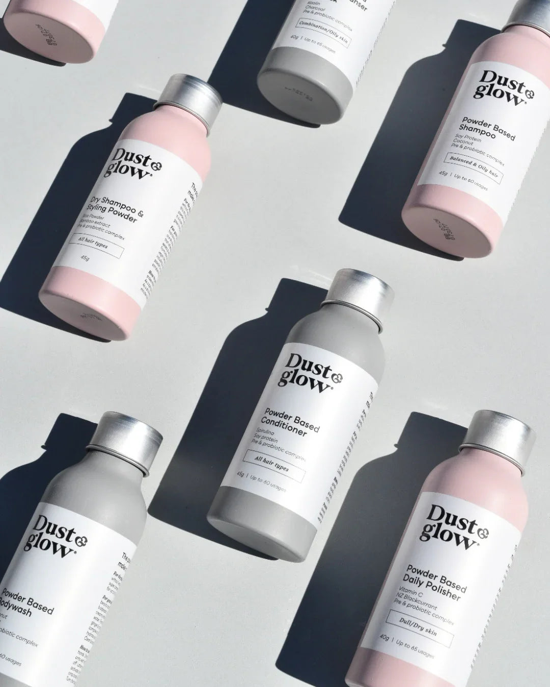 Eco-friendly powder-based hair and body care bottles in pink and gray, waterless and low-tox formulas